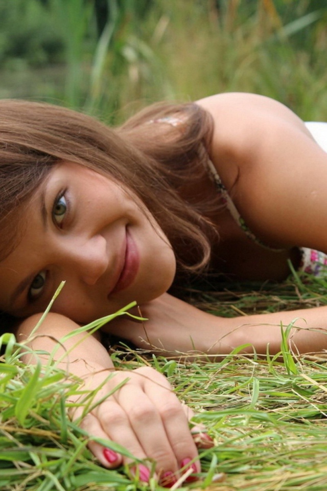 Девушка улыбается и лежит на траве