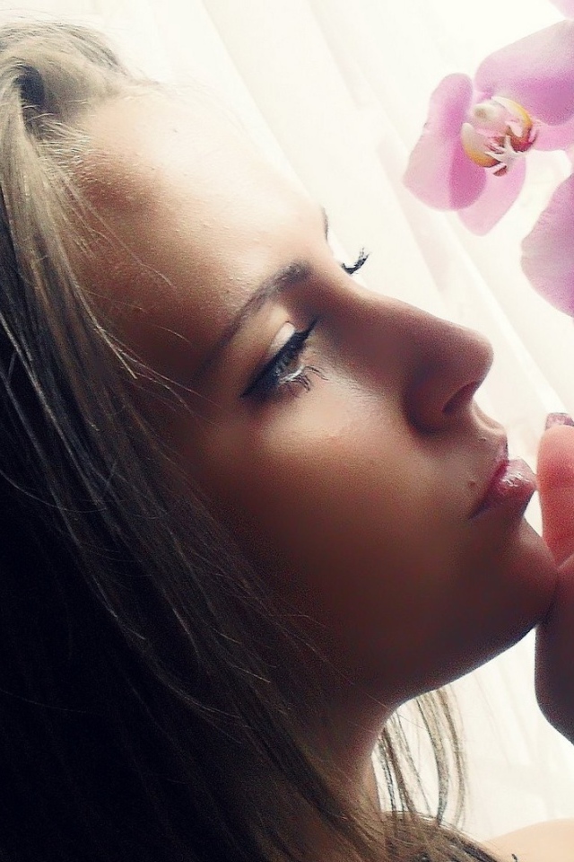 Девушка смотрит орхидею