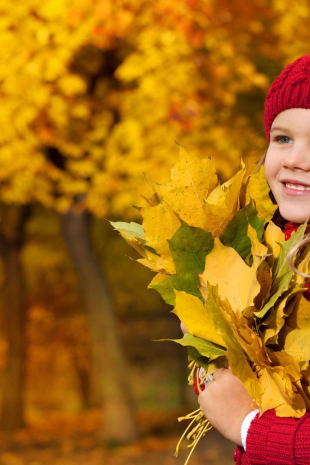 Cute baby girl is holding autumn leaves