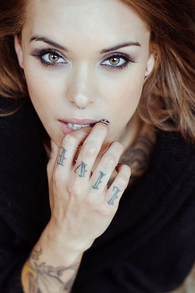 Девушка шатенка с пирсингом в носу и татуировкой на руке