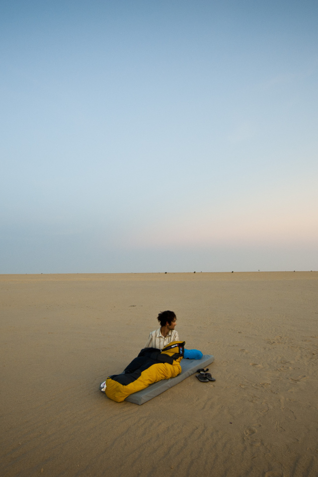 Мужчина на матрасе на пляже