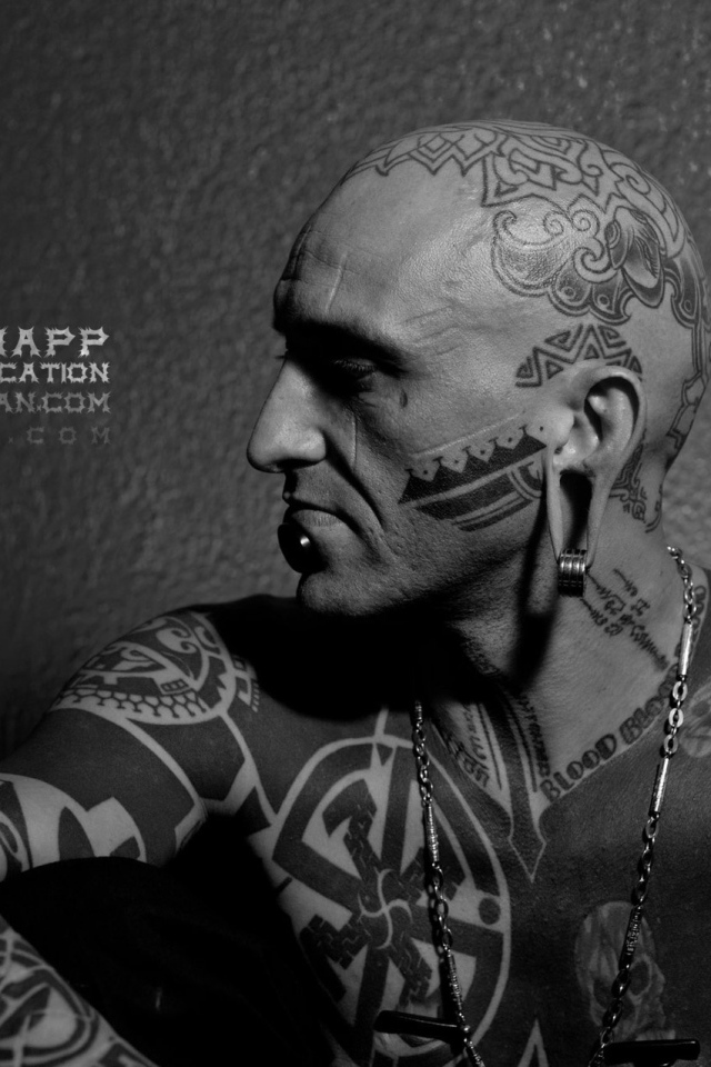 Мужчина с пирсингом в губе и татуировками