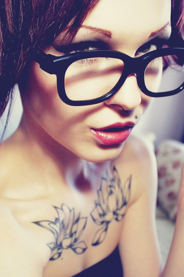 Young brunette woman with short hair wearing glasses and a lip piercing