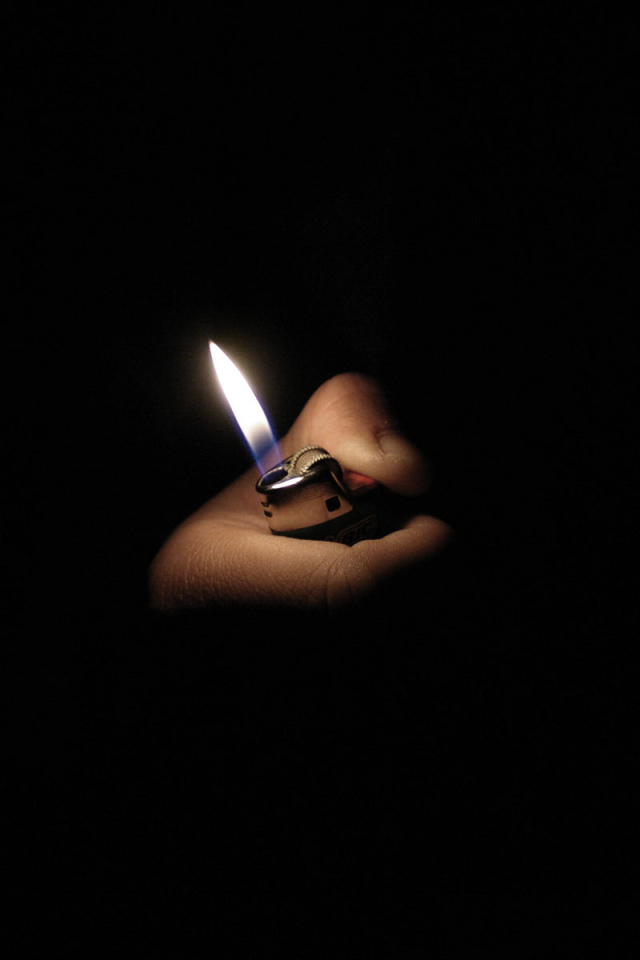 Пламя зажигалки на черных обоях