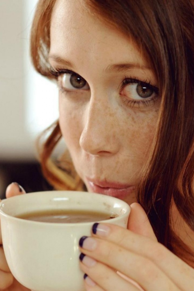 Девушка с веснушками пьет кофе