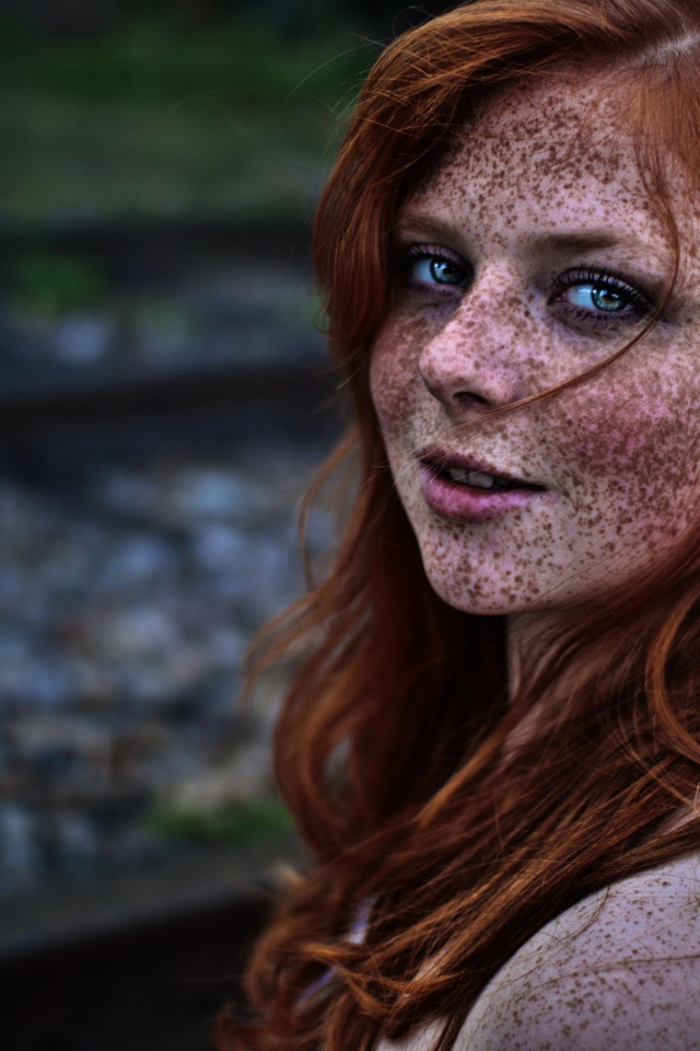 Девушка с веснушками на фоне рельс