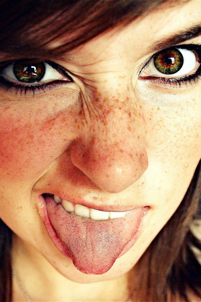 Девушка с веснушками показывает язык