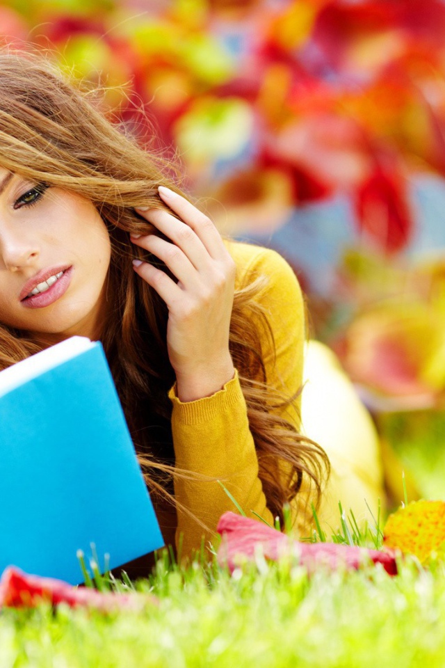 Девушка на траве читает книгу