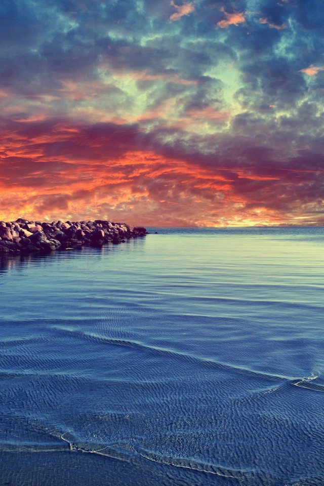 Красный закат над каменистым берегом