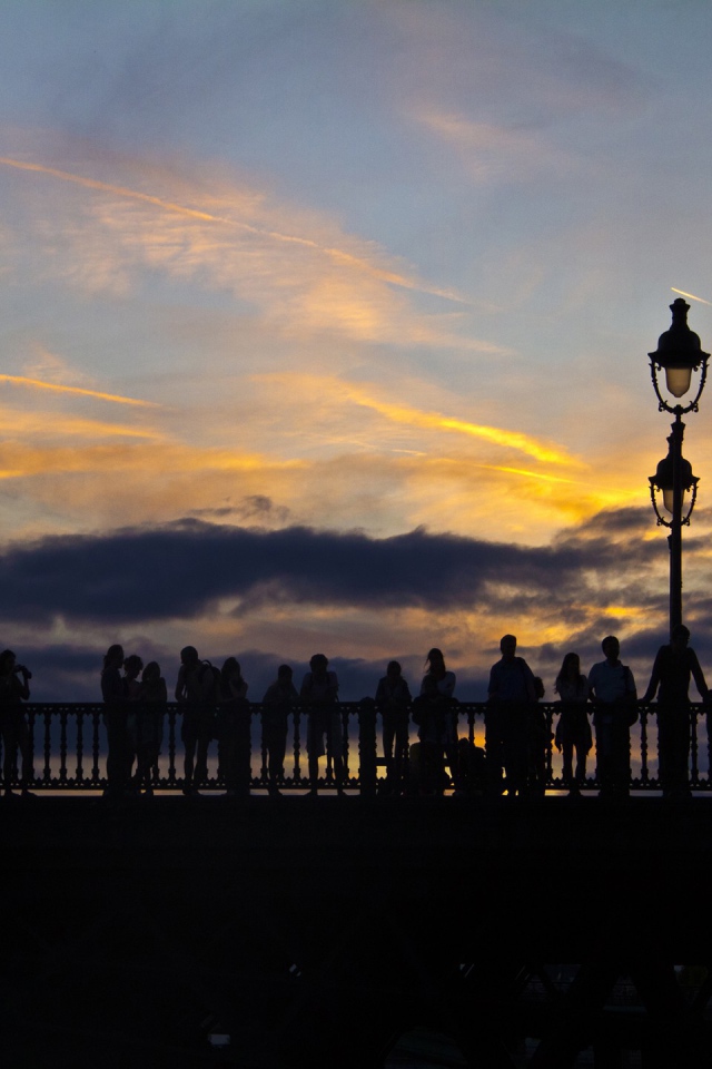 Люди провожают солнце на мосту