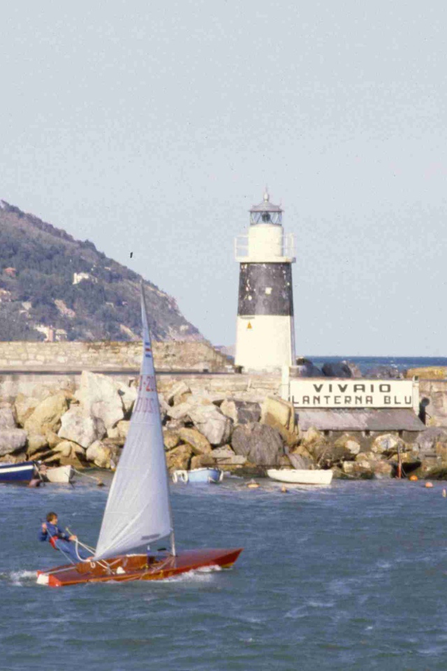 Лодка на фоне маяка на курорте Империя, Италия