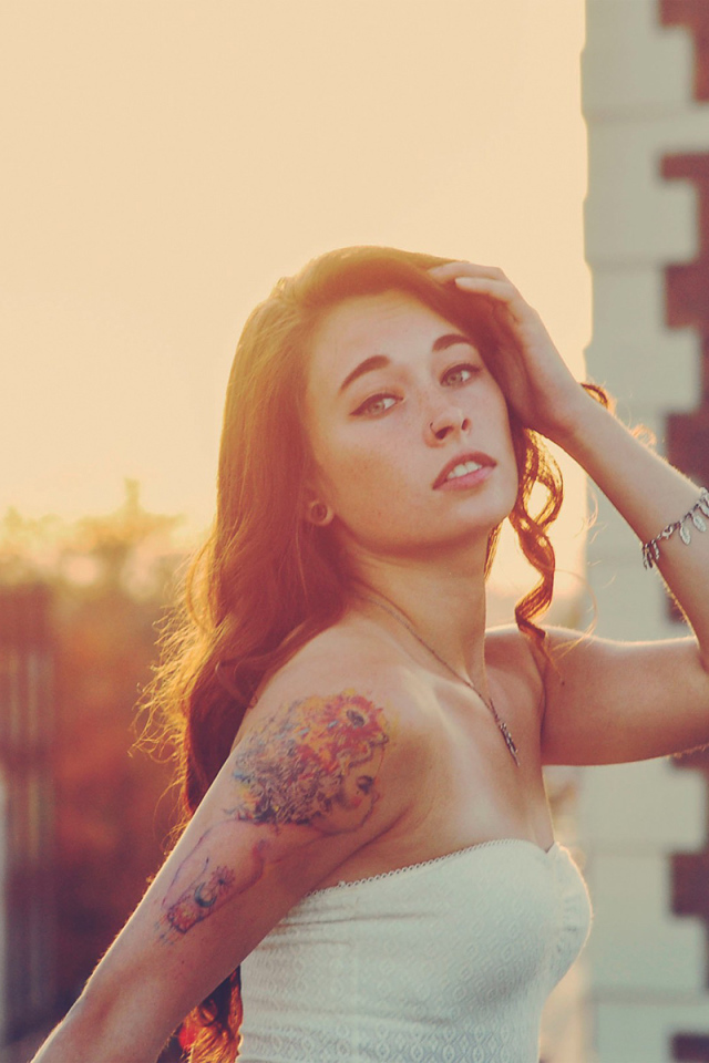 Девушка на закате с татуировкой на плече