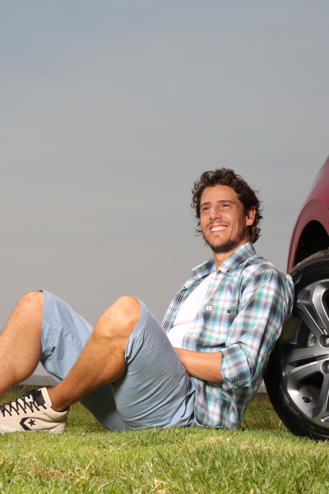 Мужчина сидит у колеса своего автомобиля