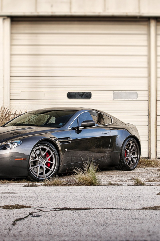 Черный Aston Martin в ворот белого ангара