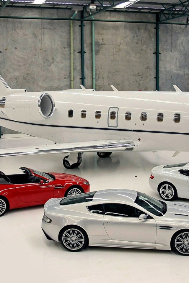 Автомобили Aston Martin в ангаре у частного самолета