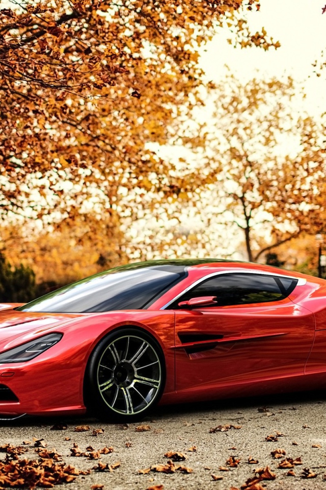 Красный Aston Martin на фоне осенних деревьев