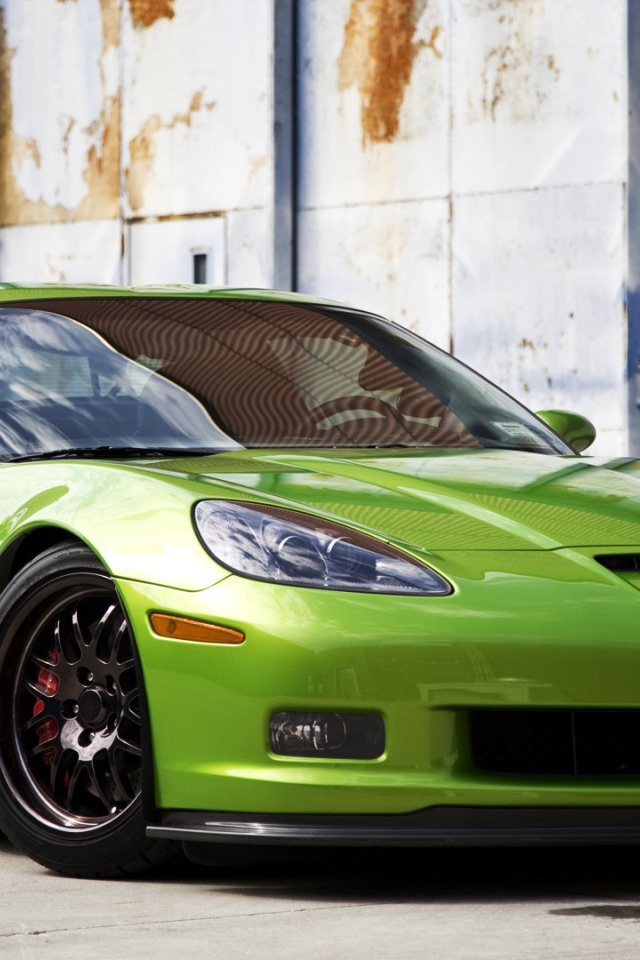 Зеленый Chevrolet Corvette на фоне стены