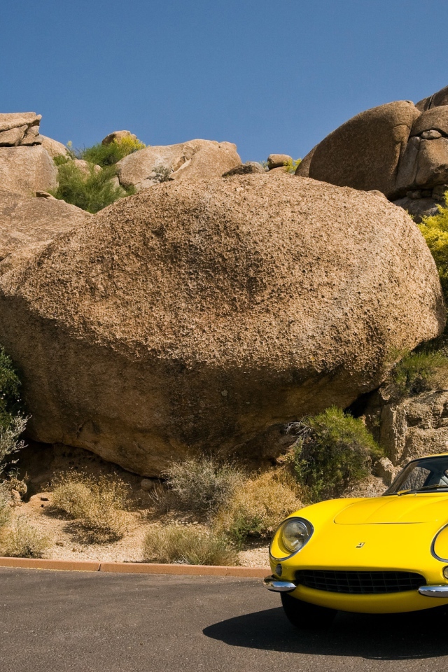 Старый желтый Ferrari у большого камня