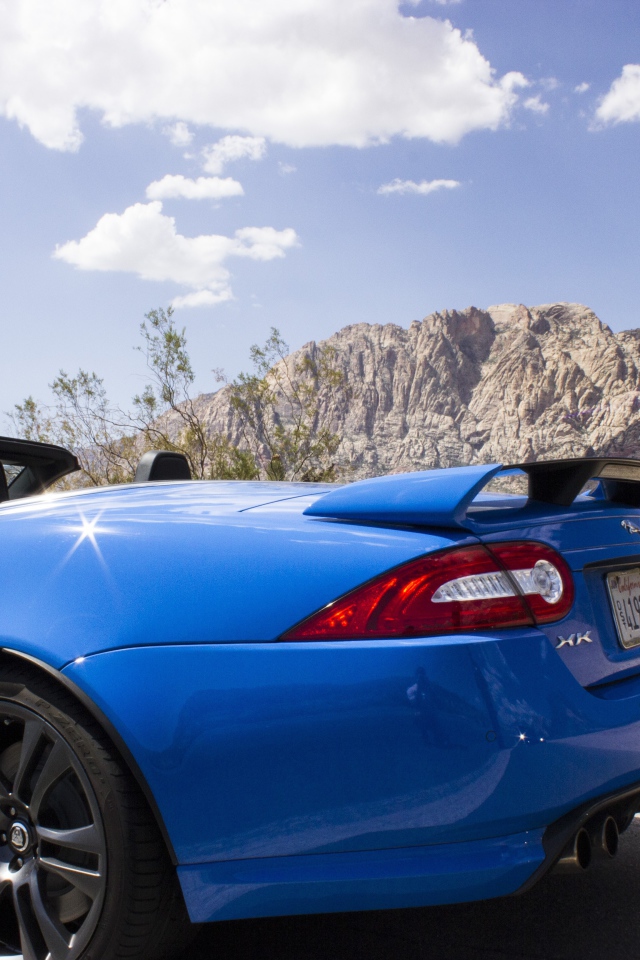 Голубой кабриолет Jaguar на фоне гор