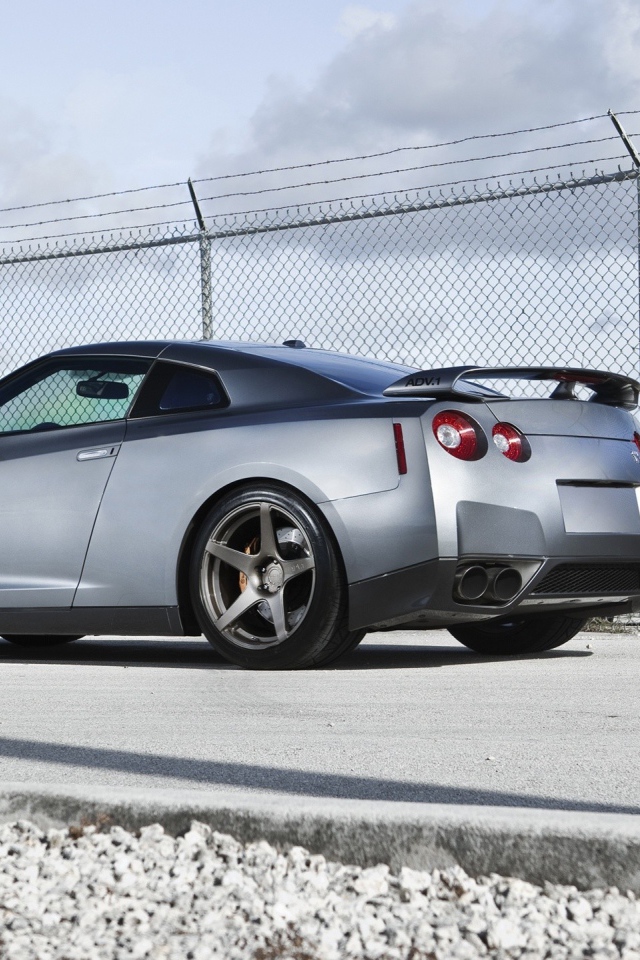 Серый Nissan Skyline GT-R R35 у забора из сетки