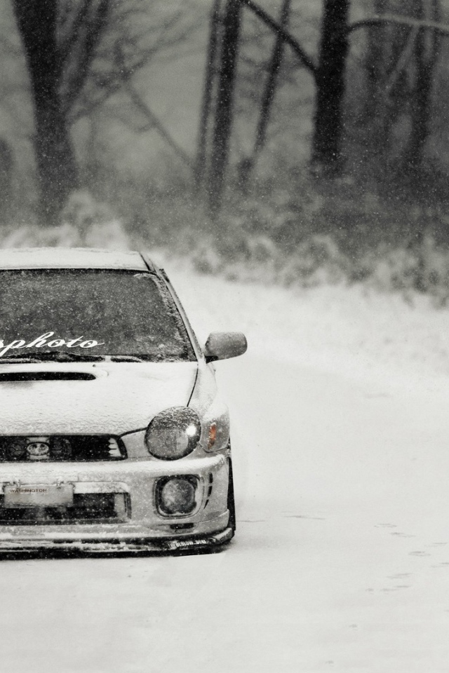 Покрытый снегом Subaru Impreza на зимней дороге