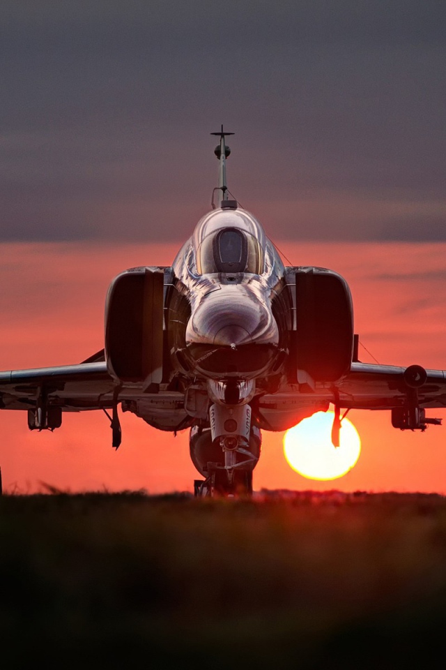 Истребитель F-4 Phantom II стоит на фоне заката