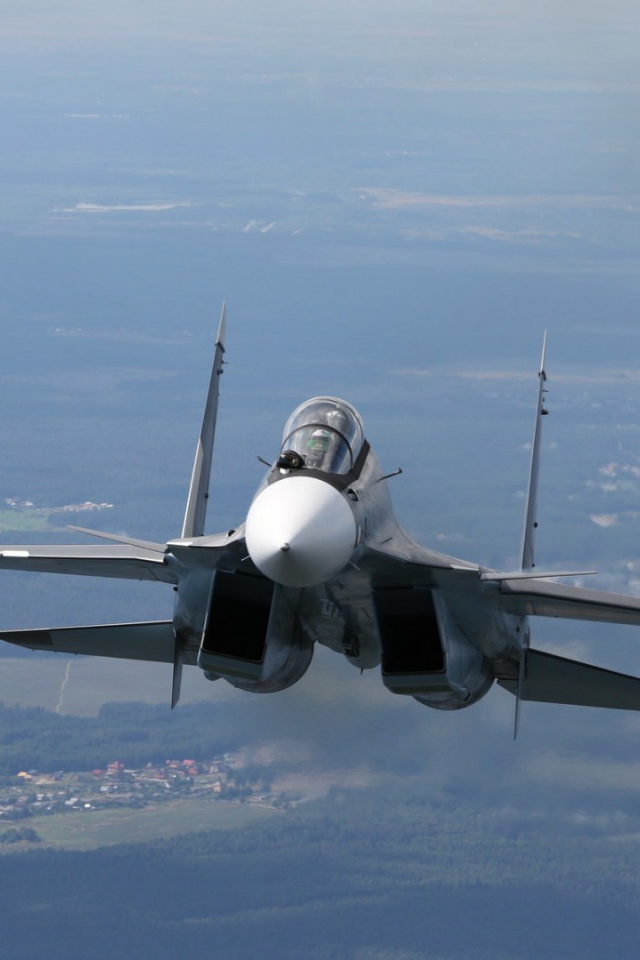 Самолет СУ-27 летит над городом