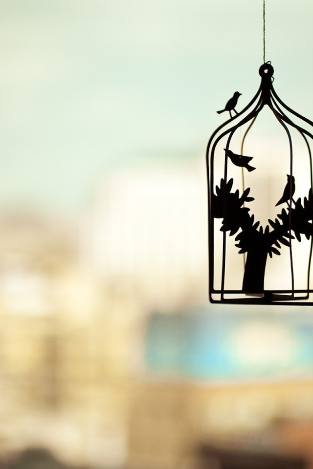 Силуэт клетки для птиц на нечетком фоне