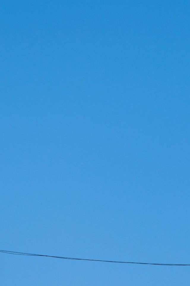 Кеды висят на проводе на фоне голубого неба