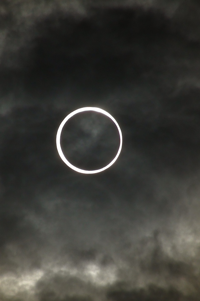 Белый круг на фоне темных облаков