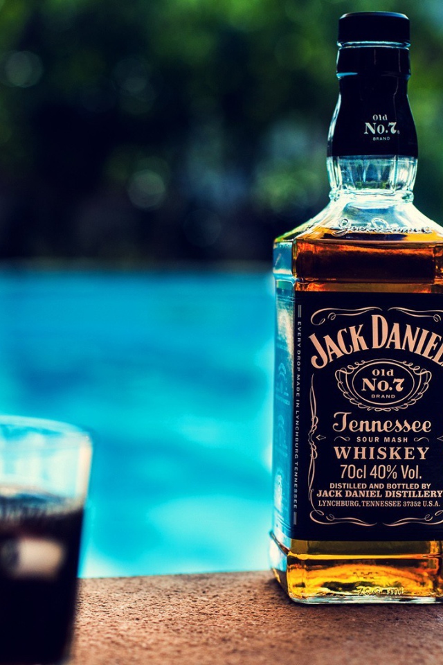 Бутылка с алкоголем на краю бассейна