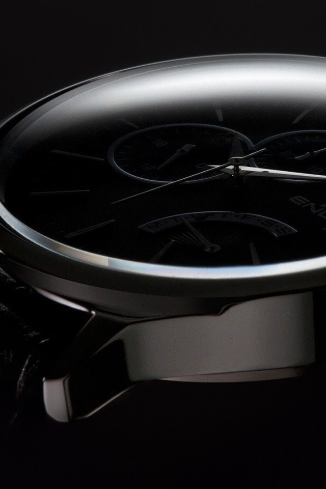 Дорогие черные часы на черном фоне