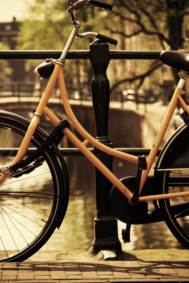 Оранжевый велосипед прислонен к перилам