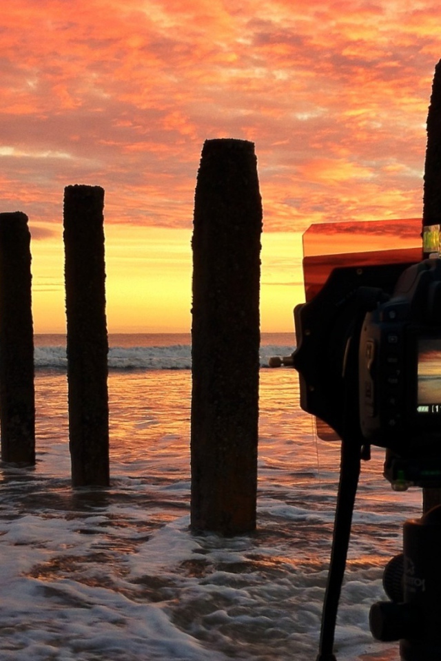 Фотограф снимает закат на берегу моря