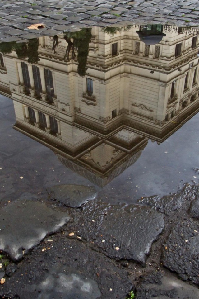 Отражение городского здания в луже
