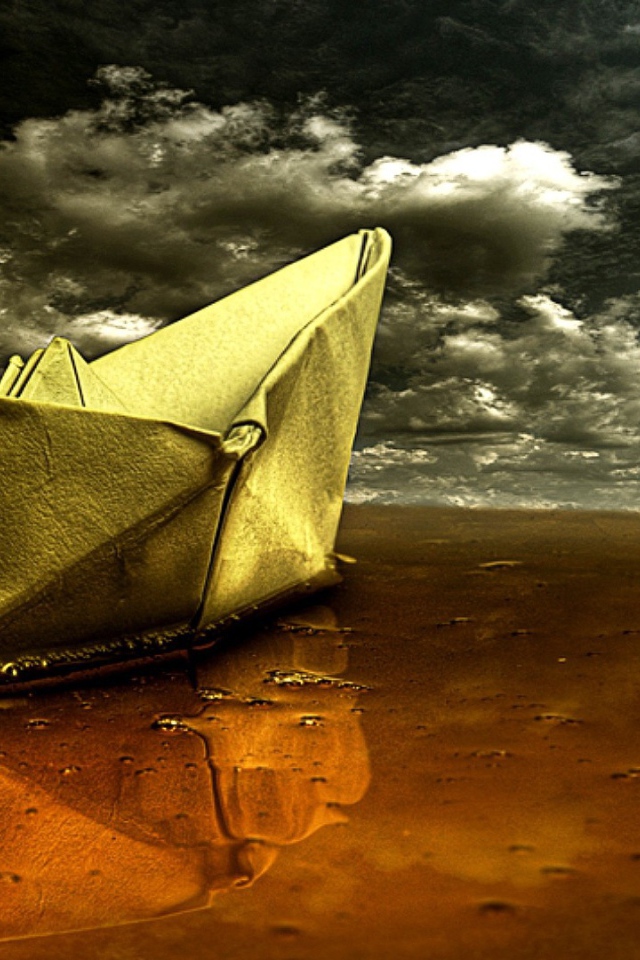 Корабль из бумаги на мокром песке