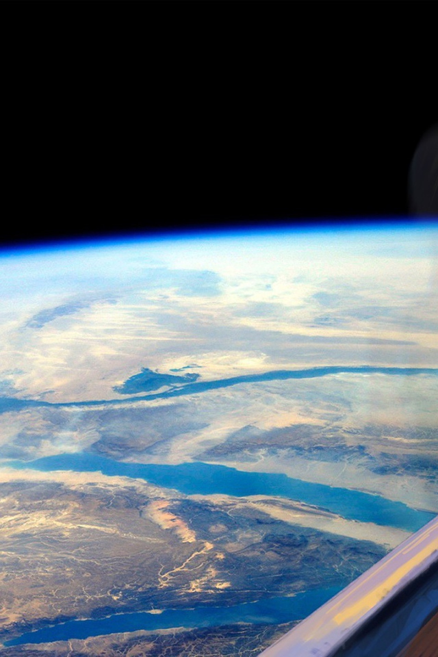 Девушка блондинка смотрит в окно на Землю