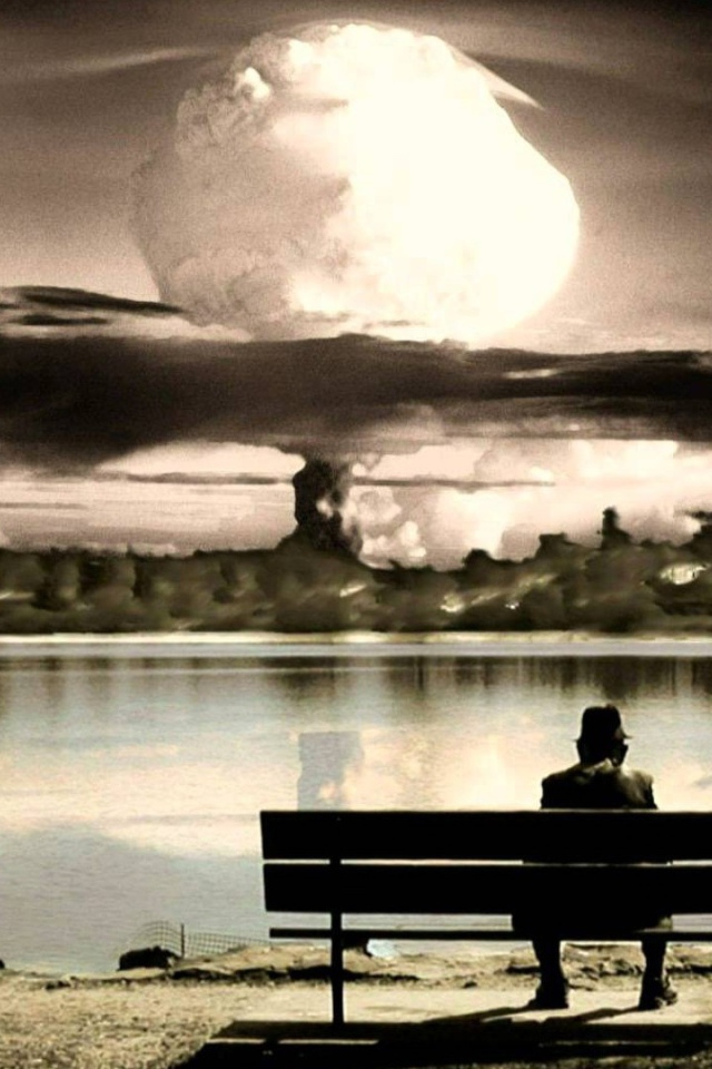 Человек смотрит на ядерный взрыв сидя на скамье