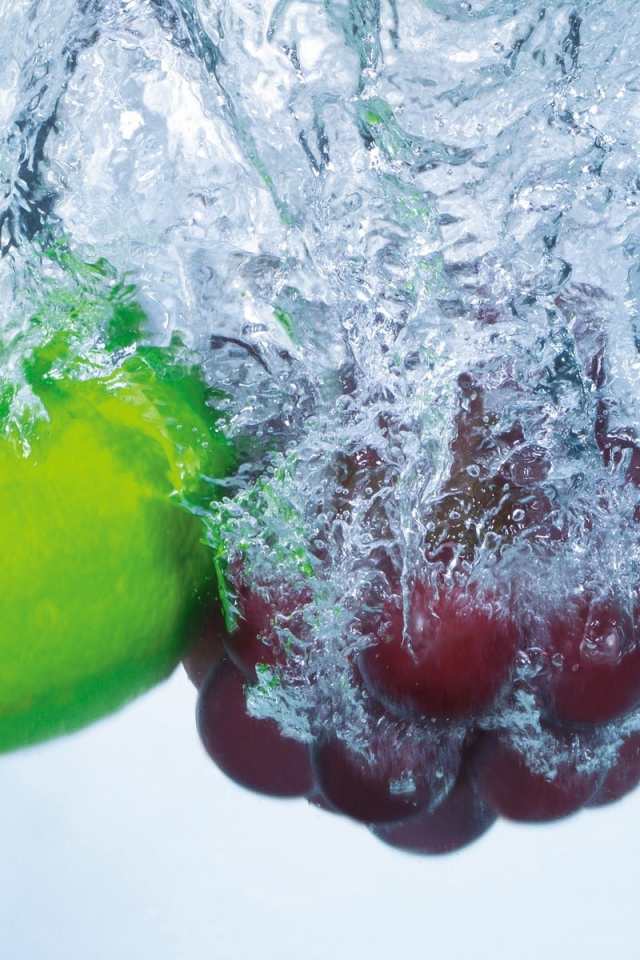 Зеленый лимон и кисть винограда в воде