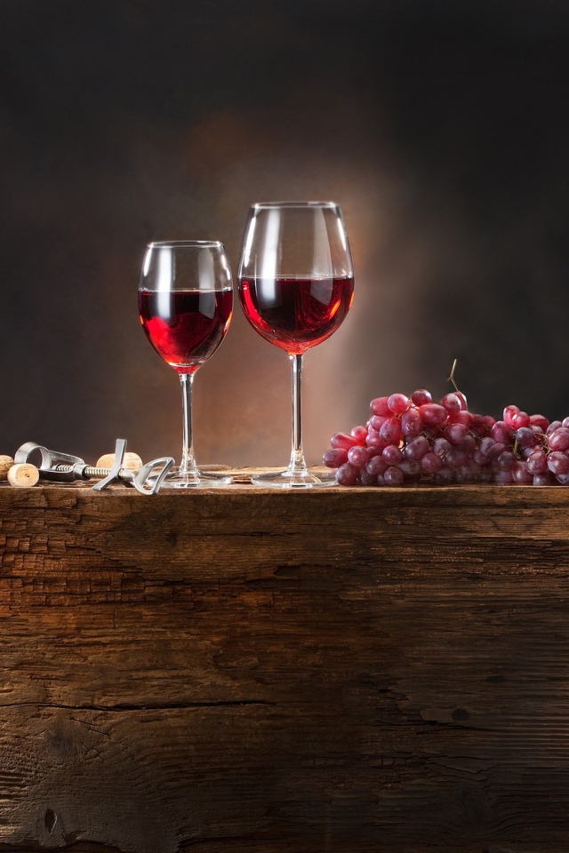 Красное вино и виноград на деревянной подставке