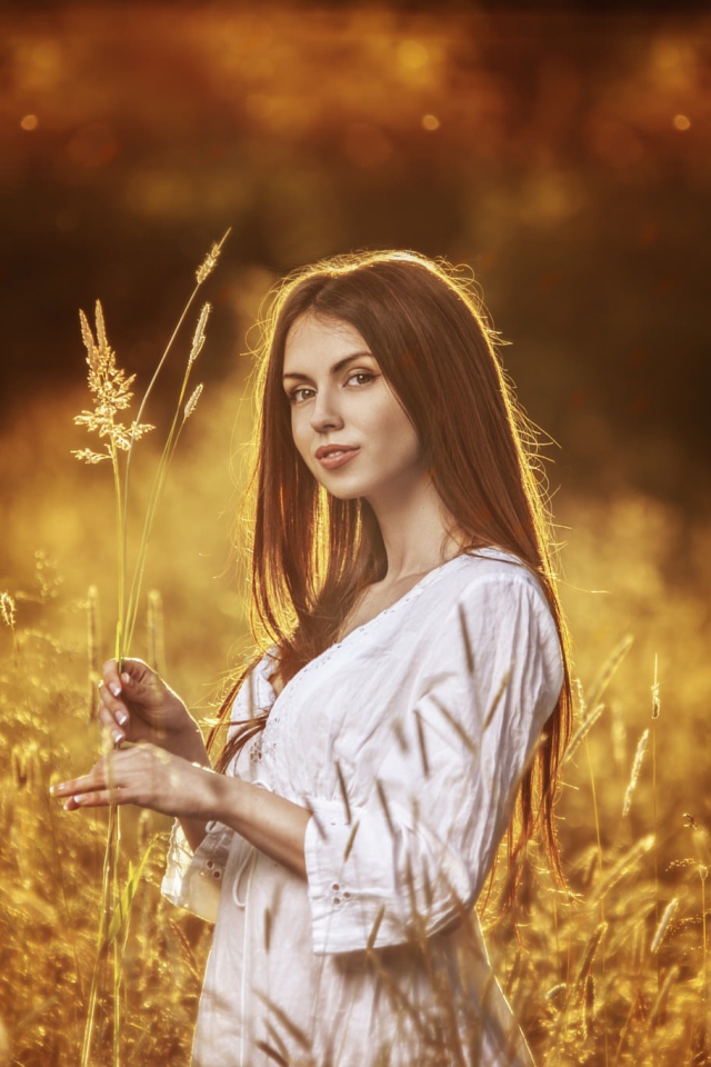 Девушка в белом платье держит в руке колоски