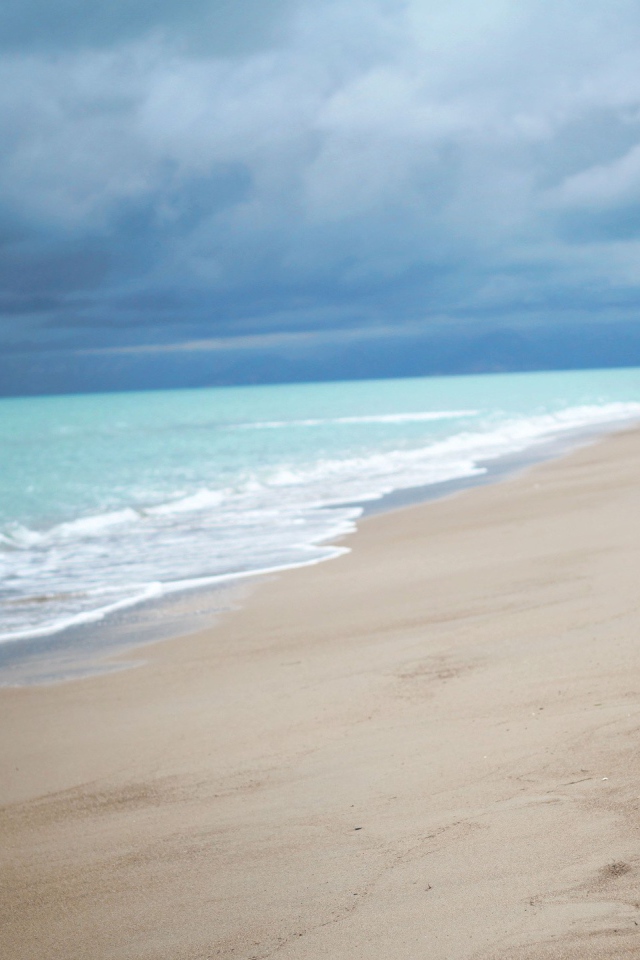 Девушка в белом платье идет по пляжу