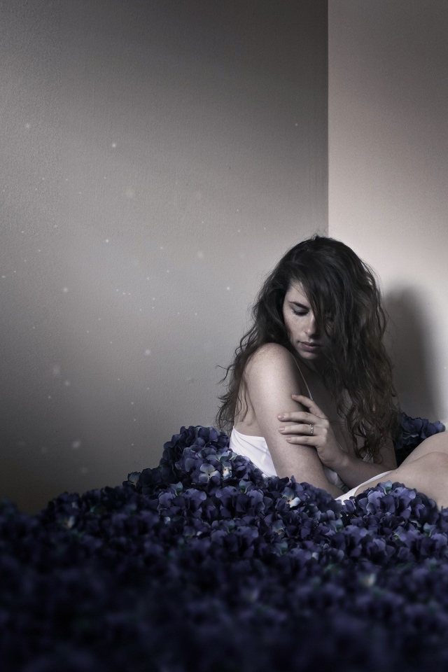 Девушка сидит в углу среди цветов