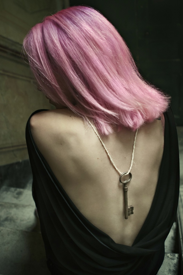 Девушка с розовыми волосами сидит на лестнице