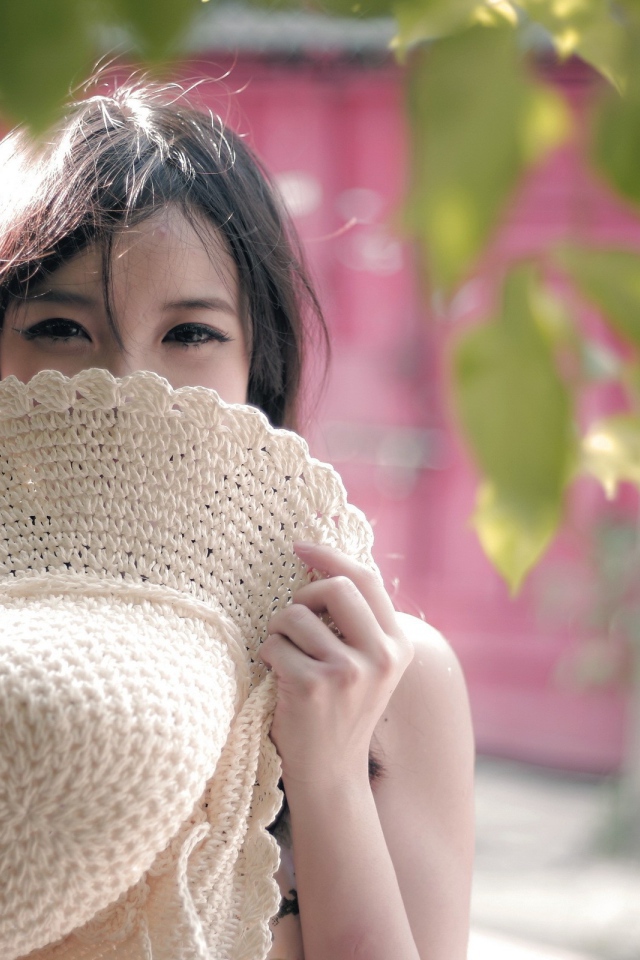 Азиатская девушка прикрыла лицо шляпой