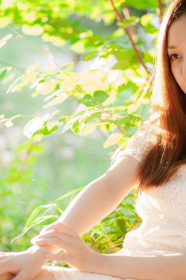 Азиатская девушка прислонилась спиной к дереву