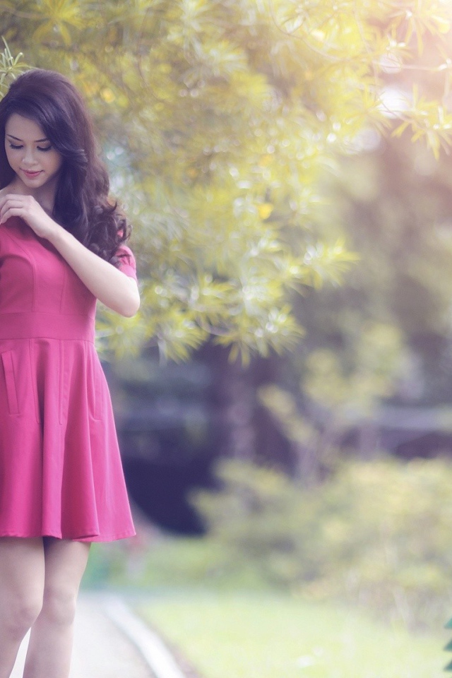 Азиатка в красном платье гуляет в саду