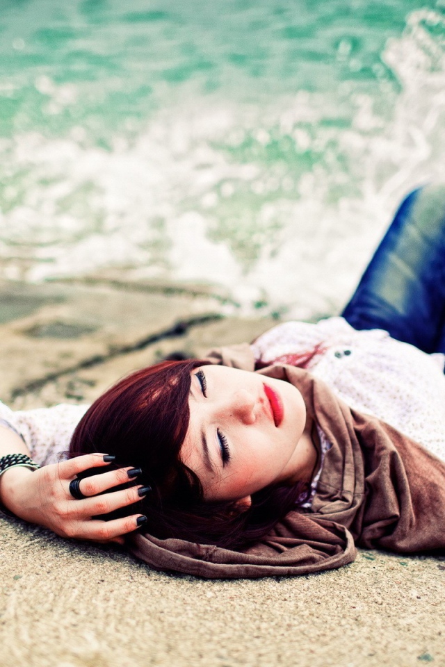 Босая девушка в джинсах лежит на набережной