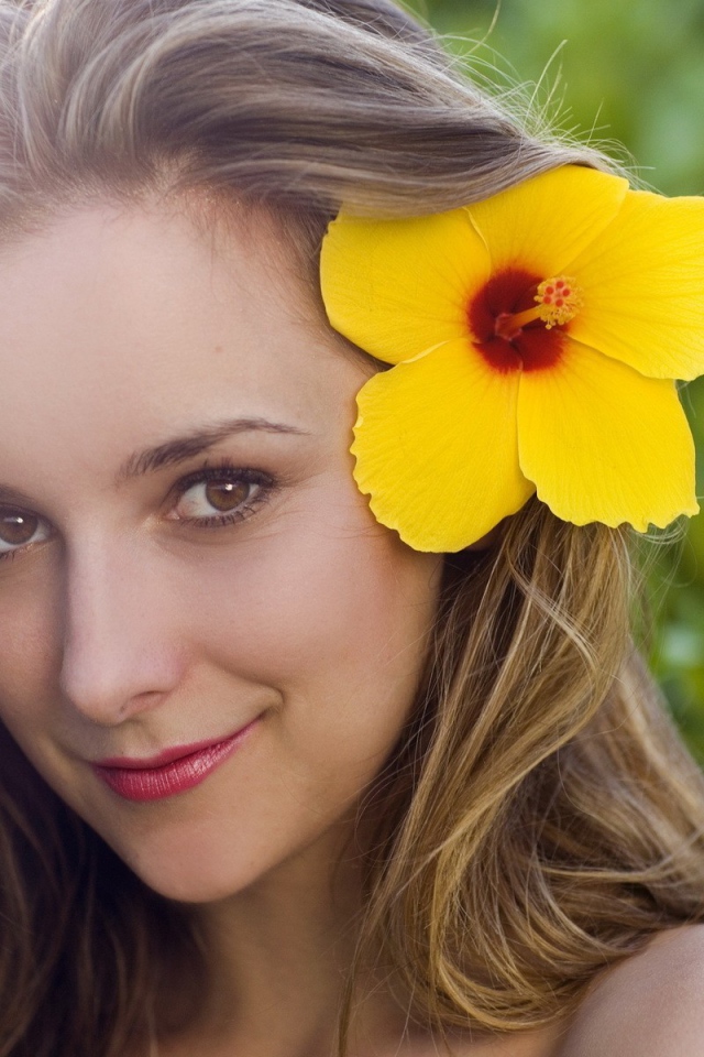 Большой желтый цветок в волосах у девушки