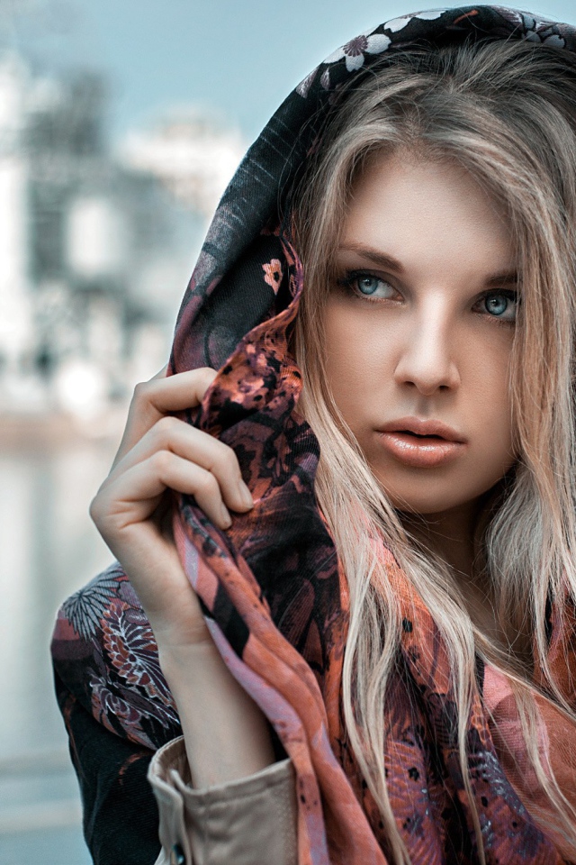 Blonde in a cloak against the backdrop of the city pond